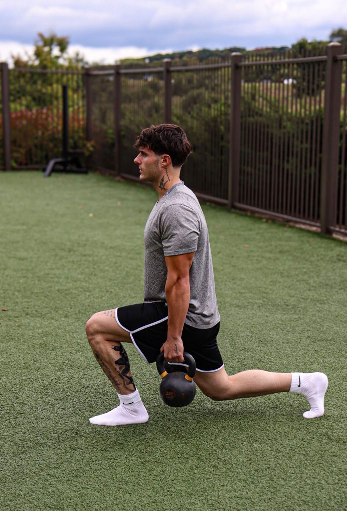 Coach is working out in the gym with dumbells.